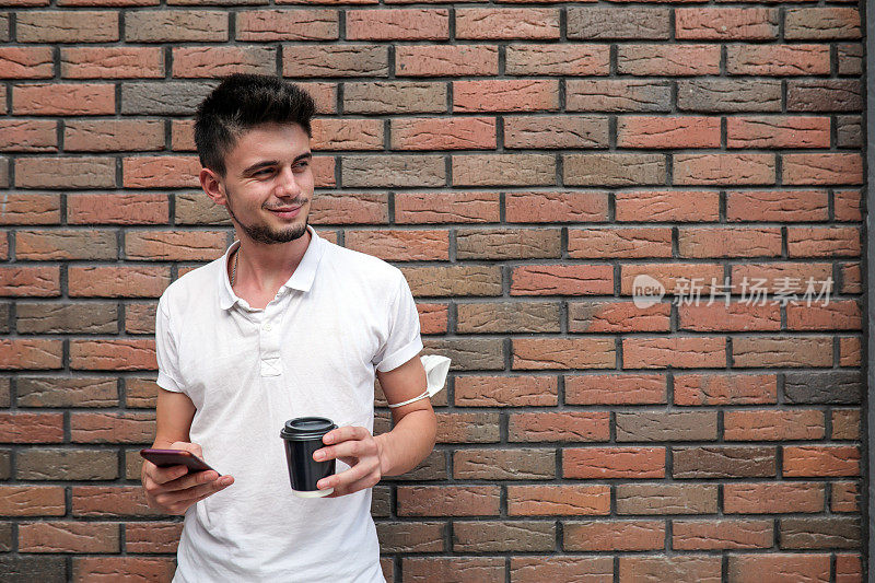 Take A Way Coffee, Man Drinking Coffee And Looking At Phone in Front Of The Stone Wall .在石墙前喝咖啡和看手机